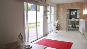 A modern hotel lobby with a reception desk, a red carpet, and a glass door leading outside. - Kristallhotel Fettehenne (Leverkusen)