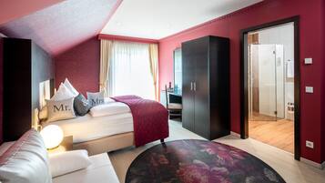 Una habitación de hotel moderna con cama, sofá, armario y zona de ducha.