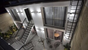 Un immeuble à plusieurs étages doté d’un escalier, de balcons et d’un espace extérieur aménagé pour s’asseoir.