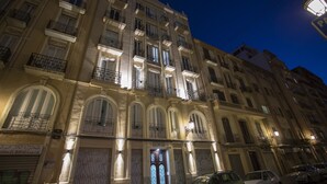 Un immeuble à plusieurs étages, doté de balcons et de fenêtres en arc de cercle, sur lequel on peut voir une enseigne indiquant « Cerceta El Baraka Hallal ».