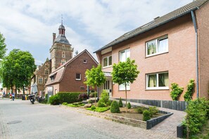 A street with traditional brick buildings, a church tower, and a paved walkway with trimmed bushes. - Hotel am Tiergarten (Raesfeld)