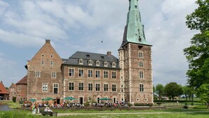A historic building with a prominent tower and a courtyard with outdoor seating. - Hotel am Tiergarten (Raesfeld)