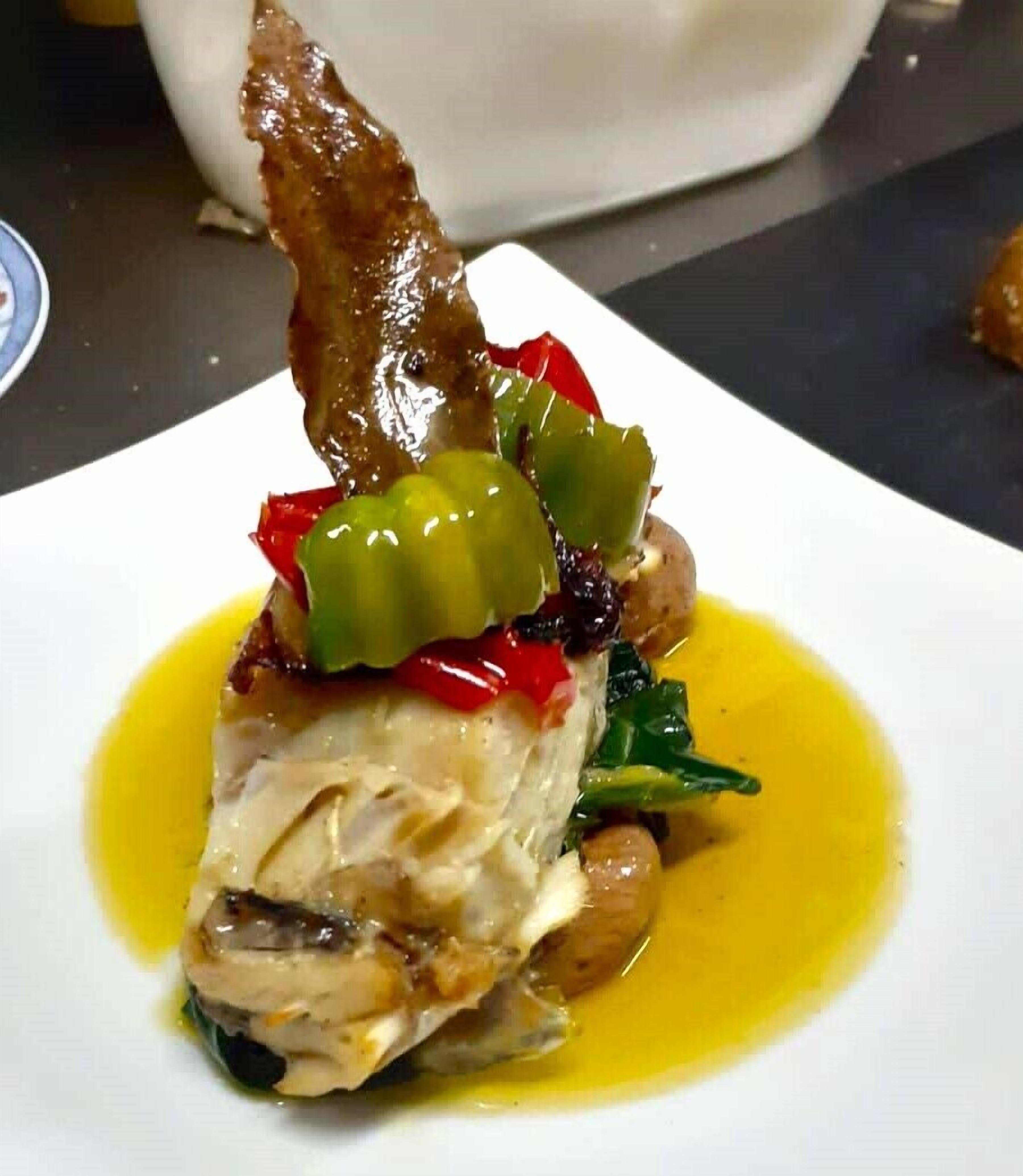 A plated dish with fish, vegetables, and a sauce.