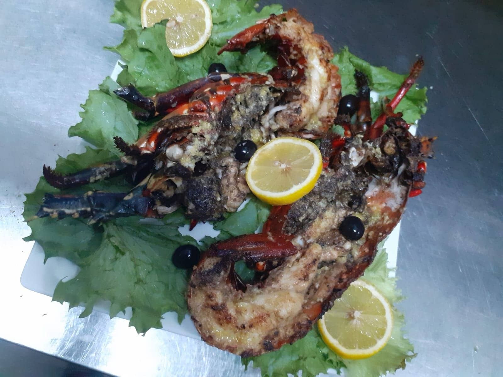 Grilled seafood on a bed of lettuce with lemon slices and olives.