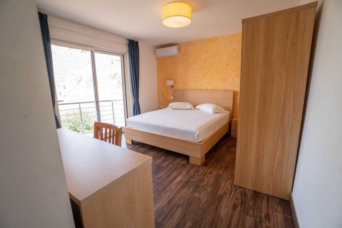Une chambre d’hôtel avec un lit, un bureau et une chaise.