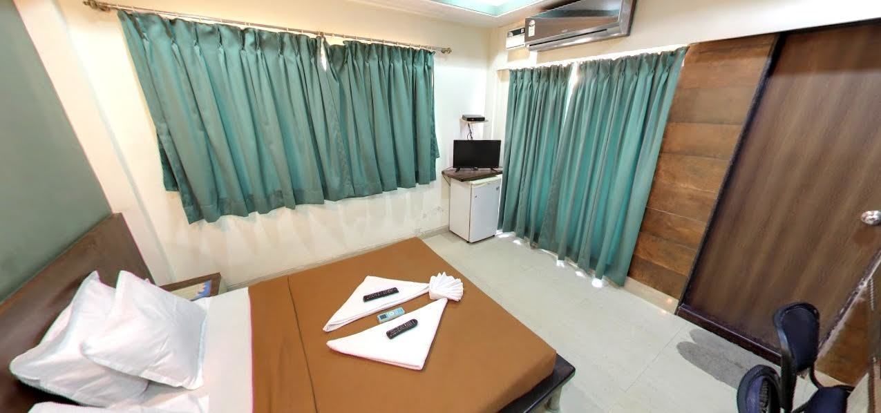 A hotel room with a bed, a desk, a chair, a TV, and curtains.