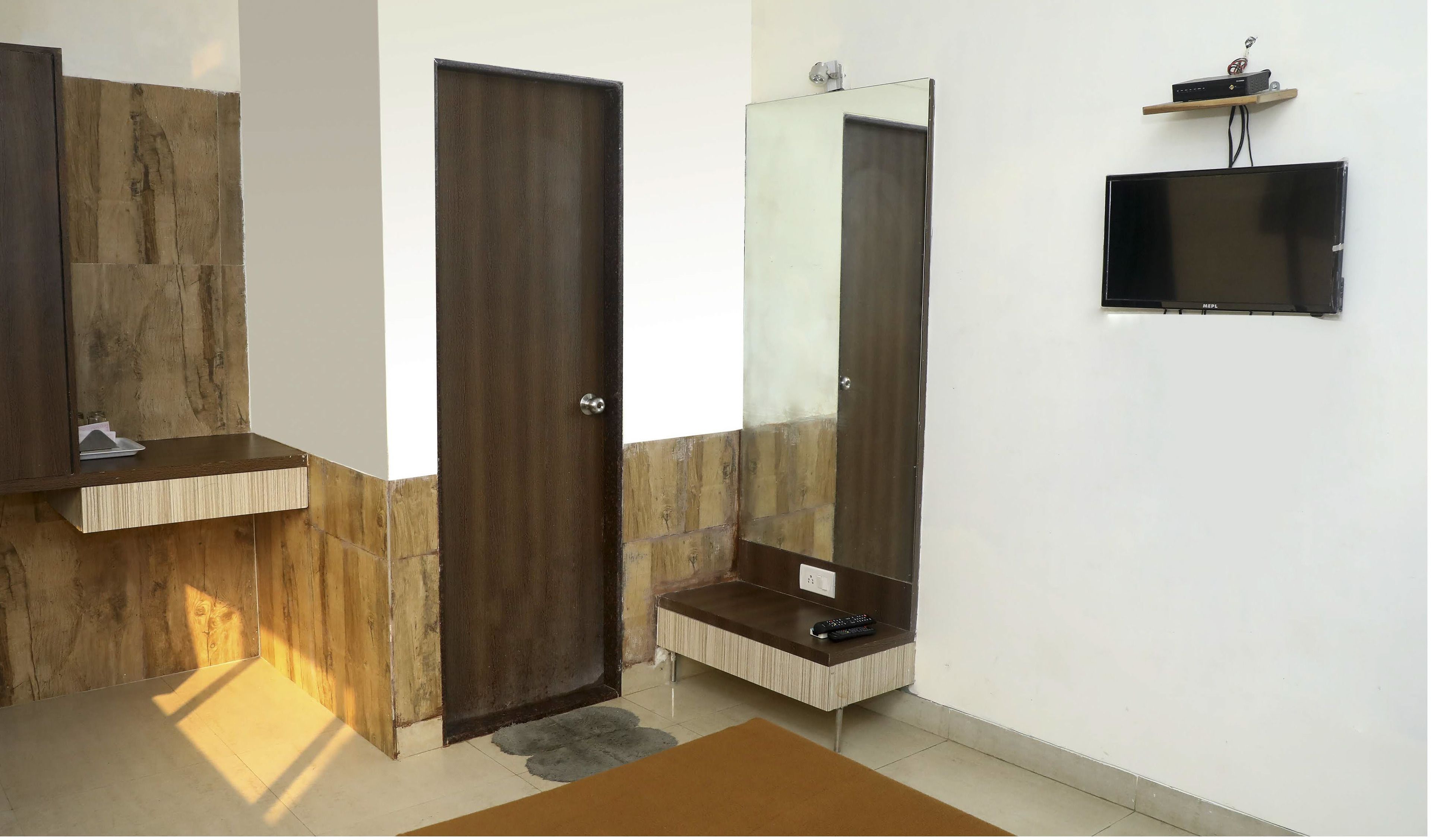 A bathroom with a wooden vanity, a large mirror, a toilet, and a mounted television.