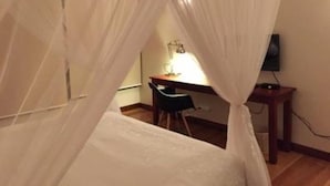 A bedroom with a canopy bed, a desk with a chair, and a television. - MyGuest (Maputo)