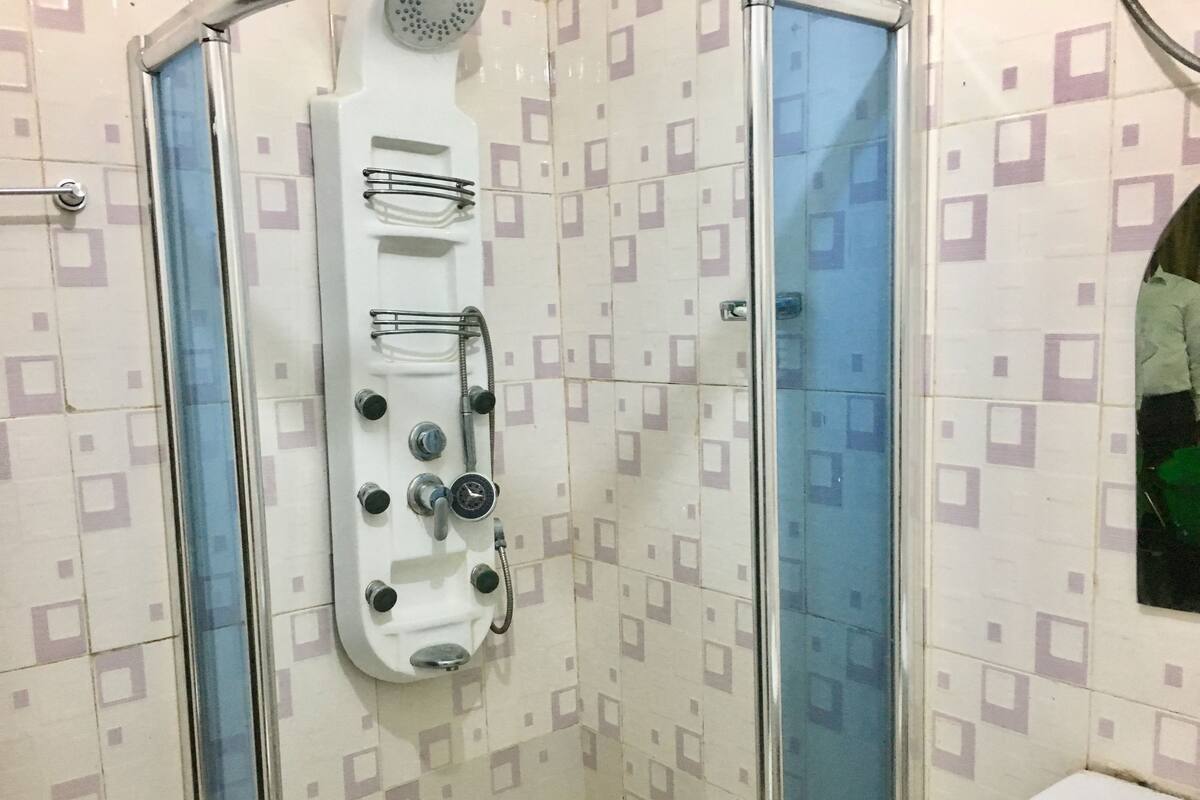 Una ducha con panel de control, puerta de cristal y un inodoro.