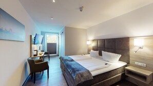 A modern hotel room with a large bed, bedside tables, a desk with a chair, and a television. - Hotel Am Stadtpark (Papenburg)