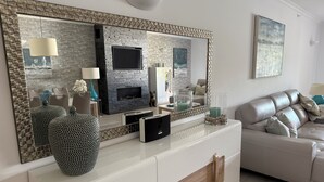 A modern living room with a fireplace, a large mirror, and a white sofa. - Luxury, spacious, two bedroom apartment on the Vill Sol Golf & Spa Resort (Quarteria)