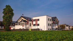 Un hôtel moderne doté d’un toit plat, de panneaux solaires et d’un grand arbre à l’avant.
