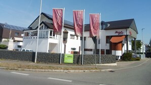 Un hôtel à la façade blanche, orné de bannières rouges et d’une enseigne.