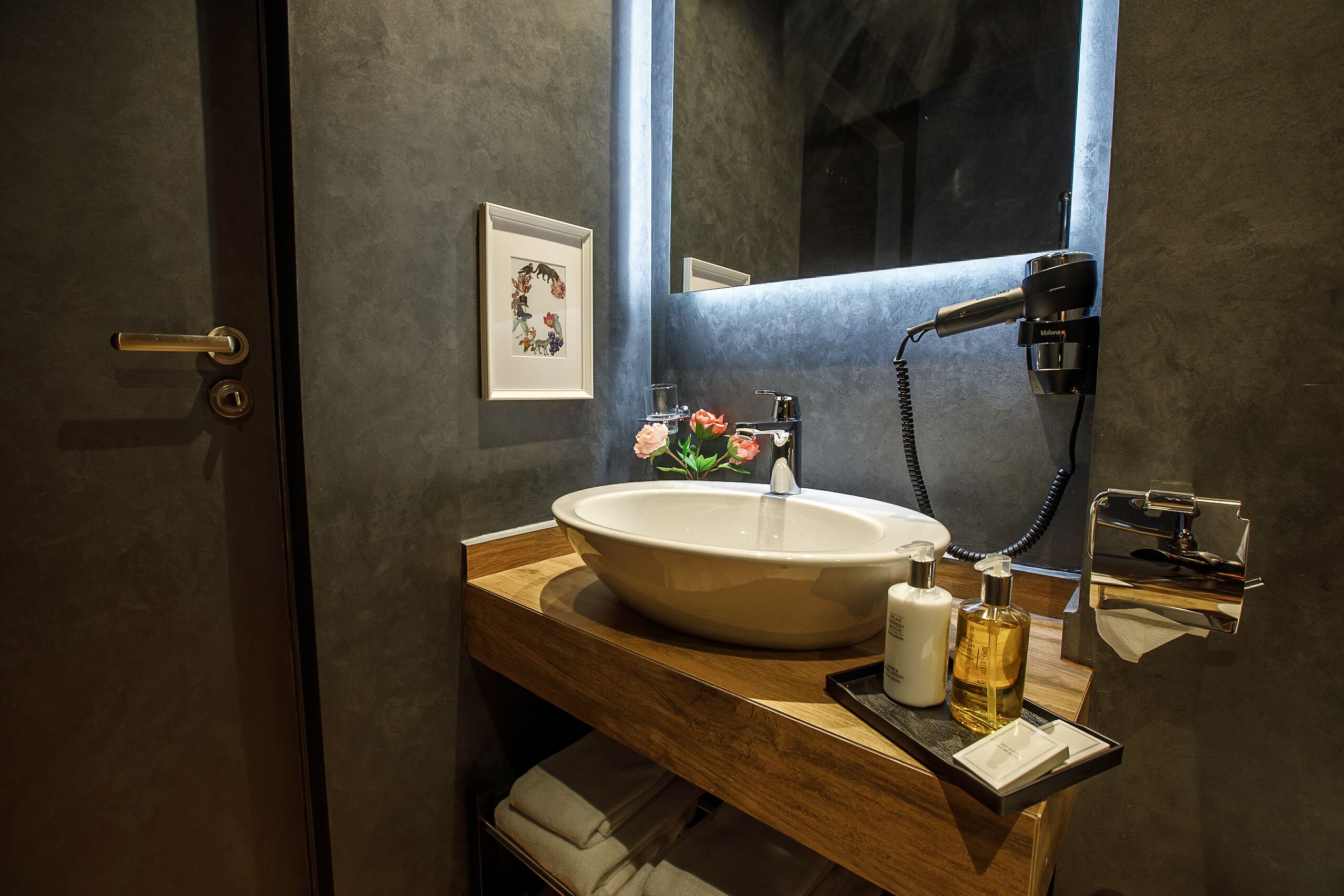 A bathroom with a large sink, a mirror, a hairdryer, and a towel rack.