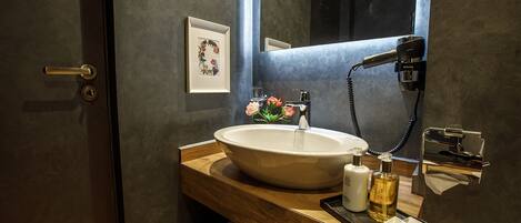 A bathroom with a large sink, a mirror, a hairdryer, and a towel rack.