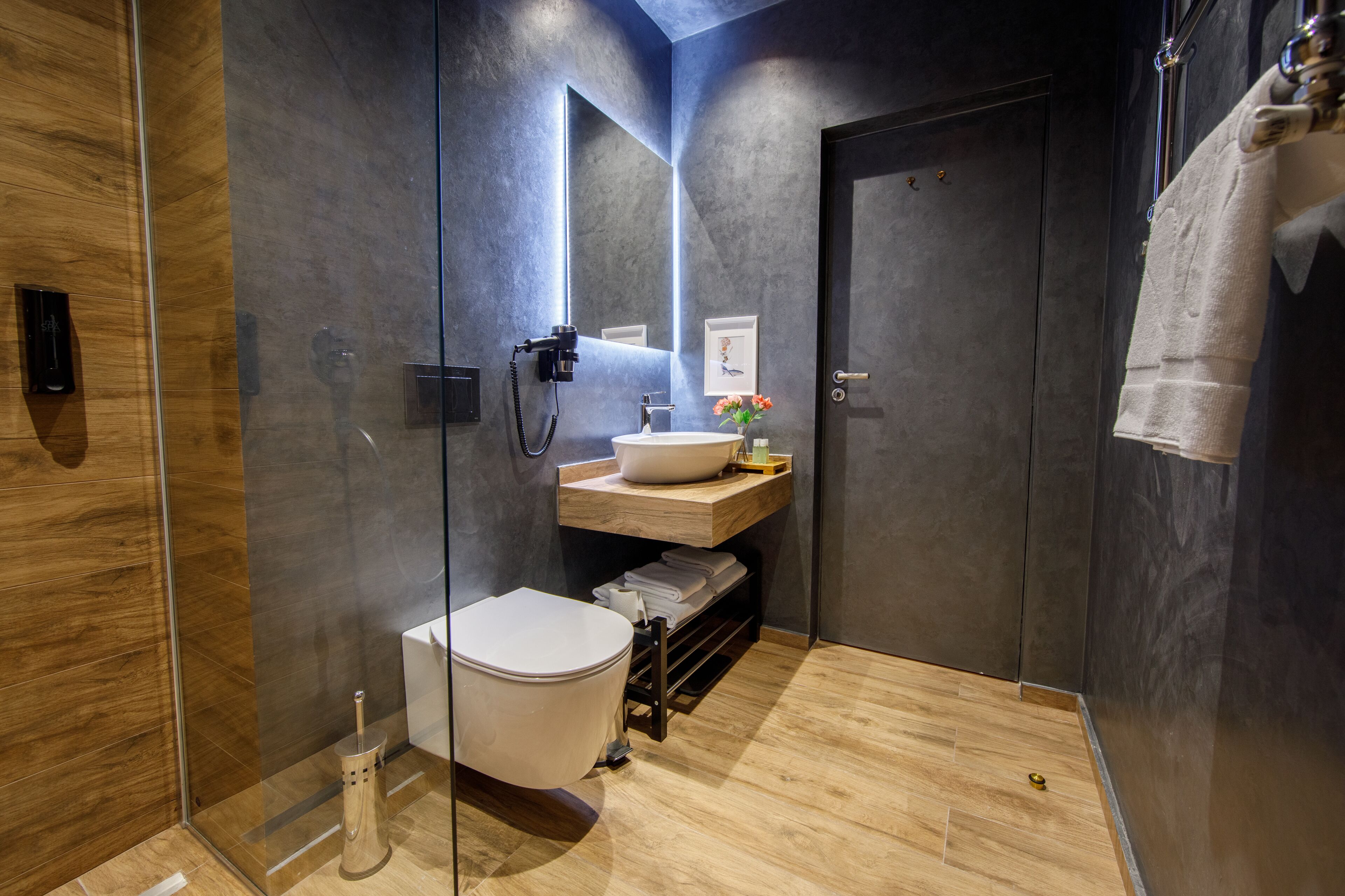 A modern bathroom with a glass-enclosed shower, a white toilet, a vanity with a sink and mirror, and a towel rack.