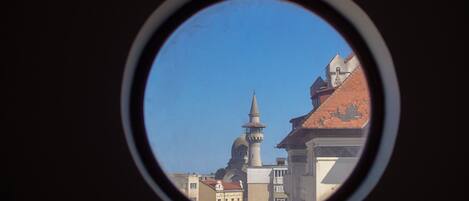 A view through a circular window of a building with a prominent tower and dome, suggesting historical architecture.