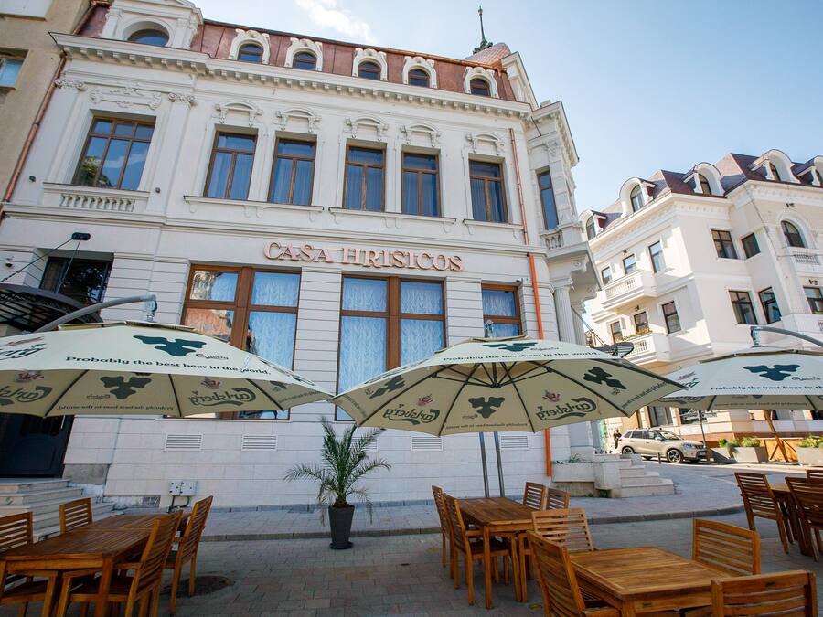 A building with the sign "Casa Hristicos" and outdoor seating with umbrellas.