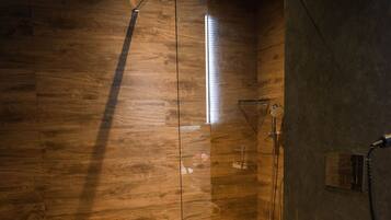 A modern bathroom with a wooden floor, a glass-enclosed shower, and a white toilet.