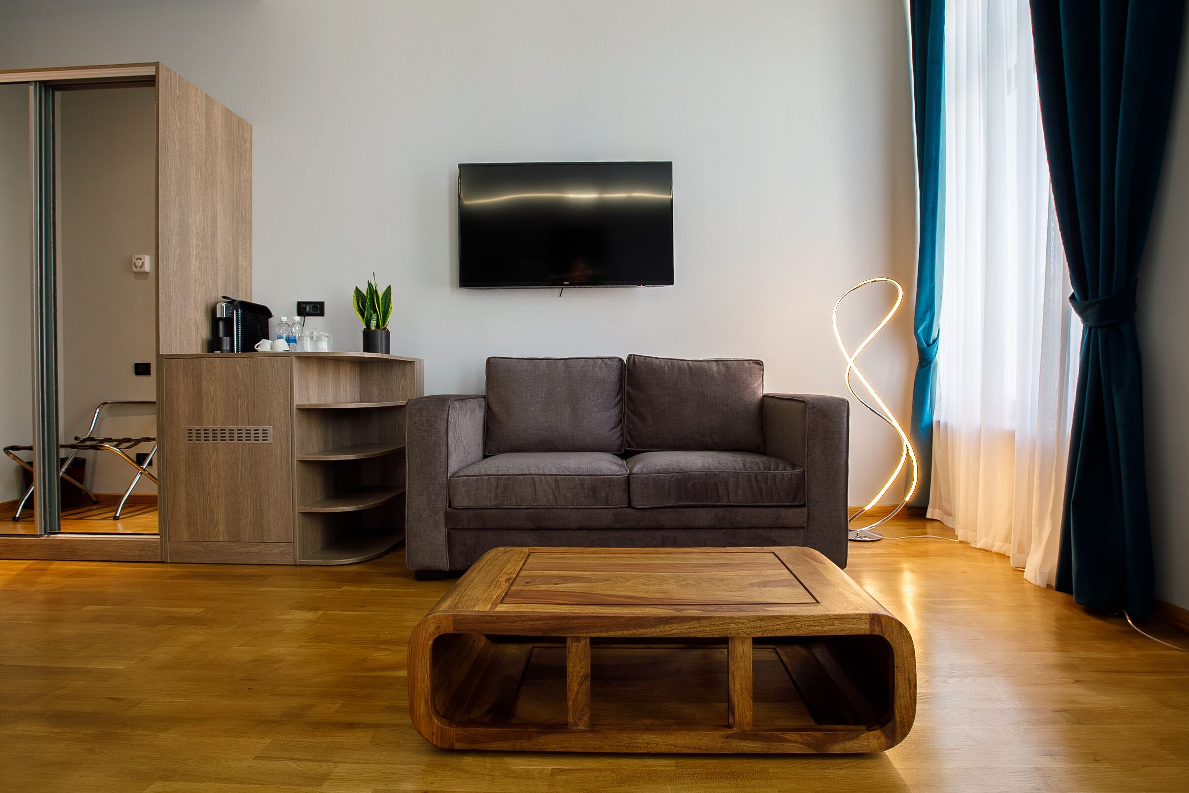 Una sala de estar moderna con una mesa de centro de madera, un sofá gris y un televisor de pantalla plana montado en la pared.
