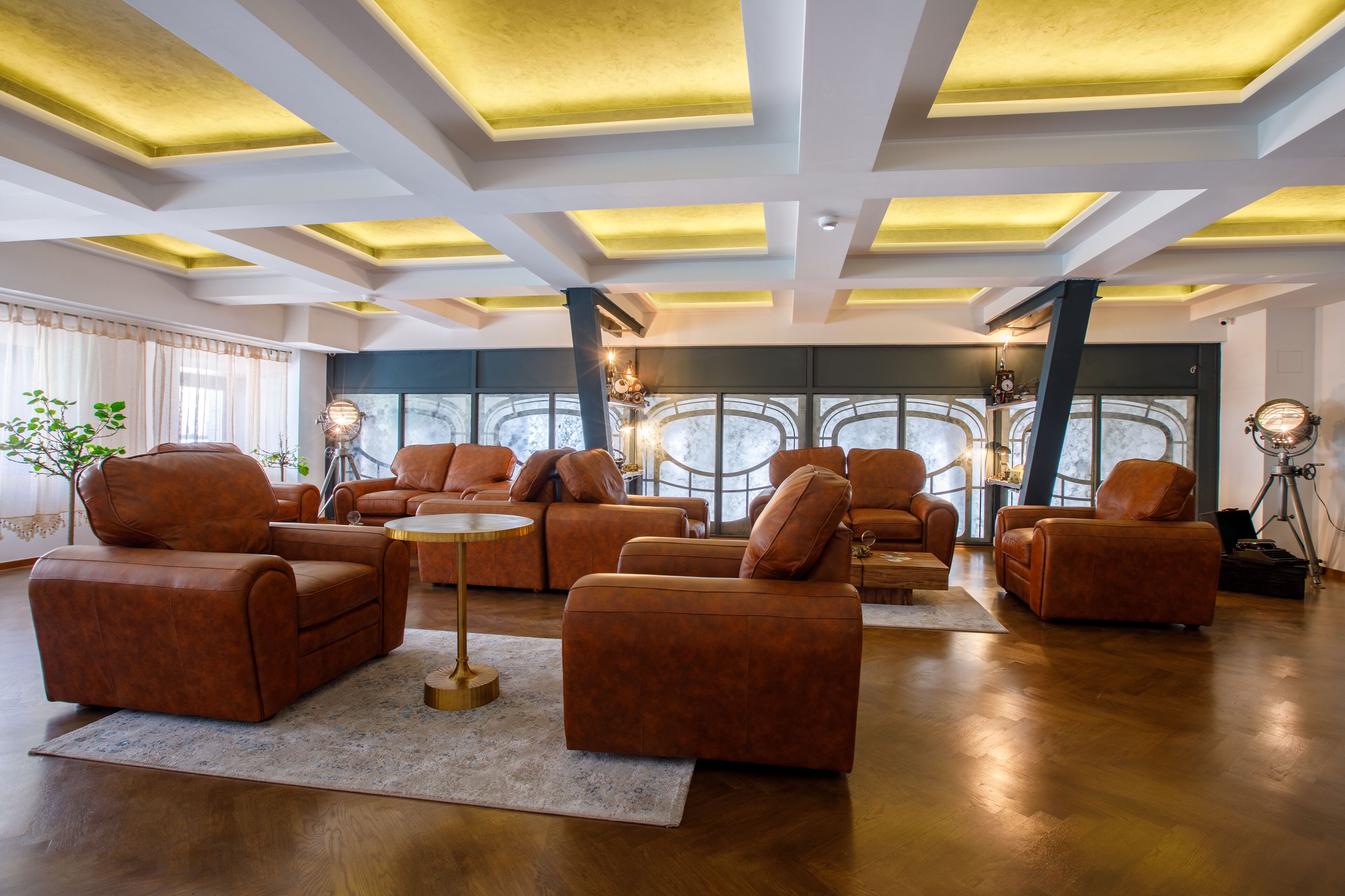 A spacious living room with leather sofas, a coffee table, and a large window with a view.