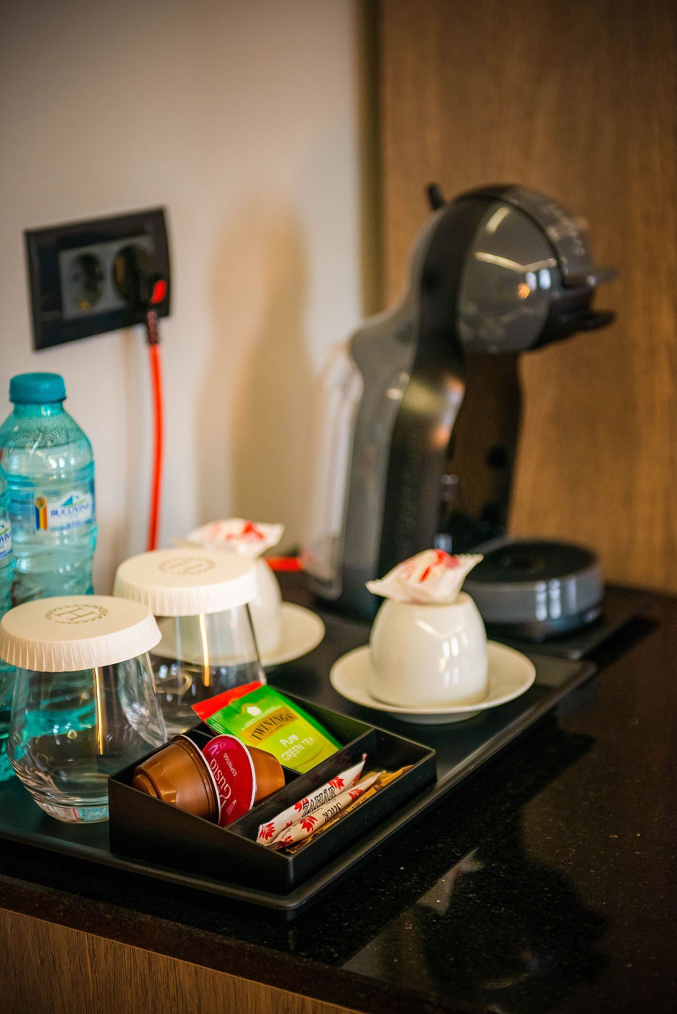 A coffee station with a coffee maker, water bottles, and various coffee pods.