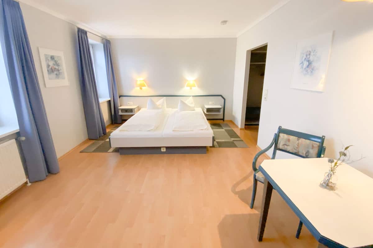 A hotel room with a bed, bedside tables, a desk, and a chair.