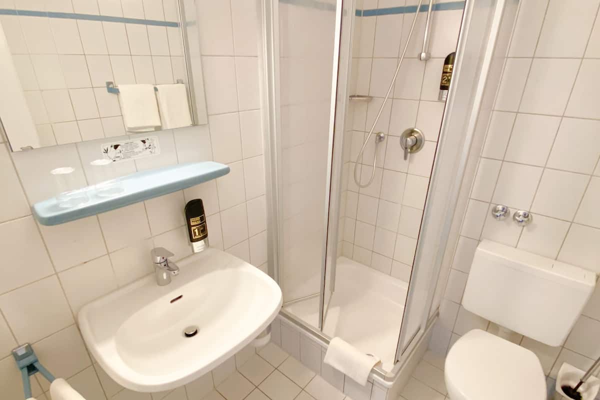 A bathroom with a sink, toilet, and glass-enclosed shower.