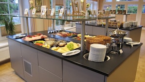 A buffet with various food items and a glass display case with framed pictures. - Hotel Wikingerhof (Kropp)