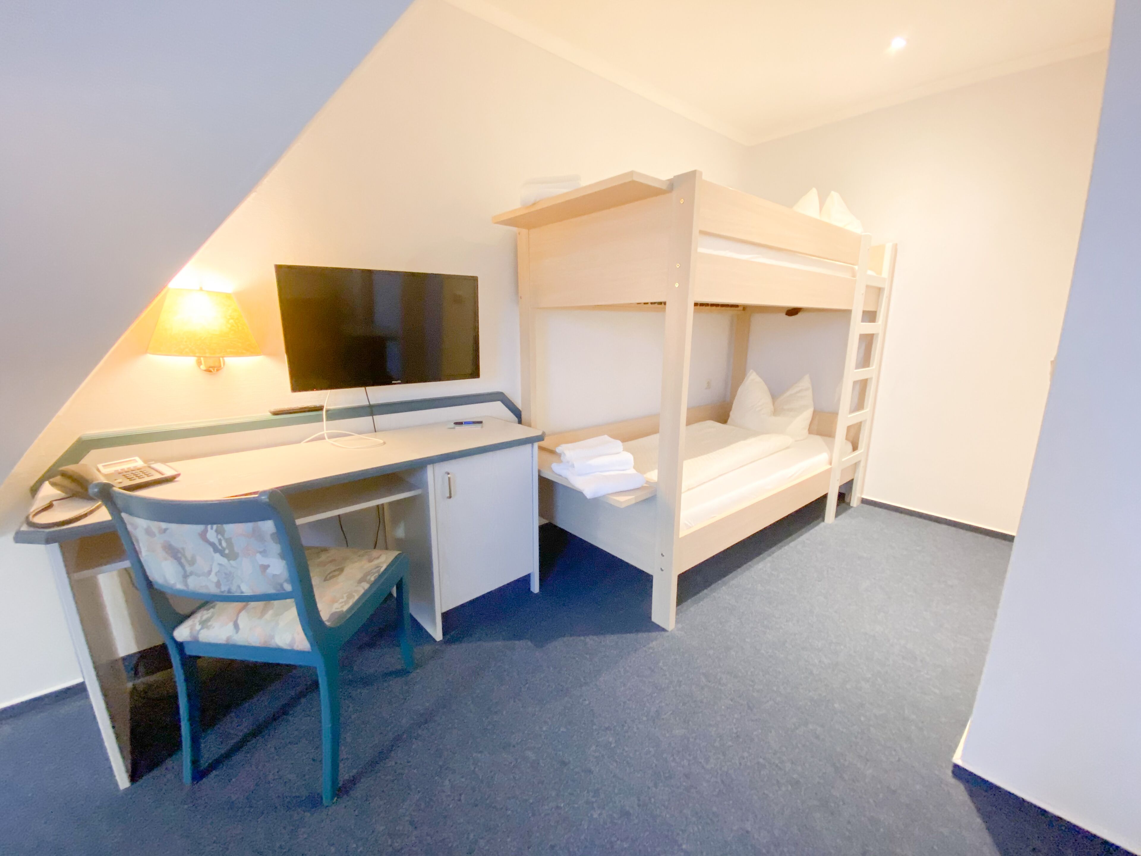 Ein Schlafsaalzimmer mit Schreibtisch, Stuhl und Fernseher.