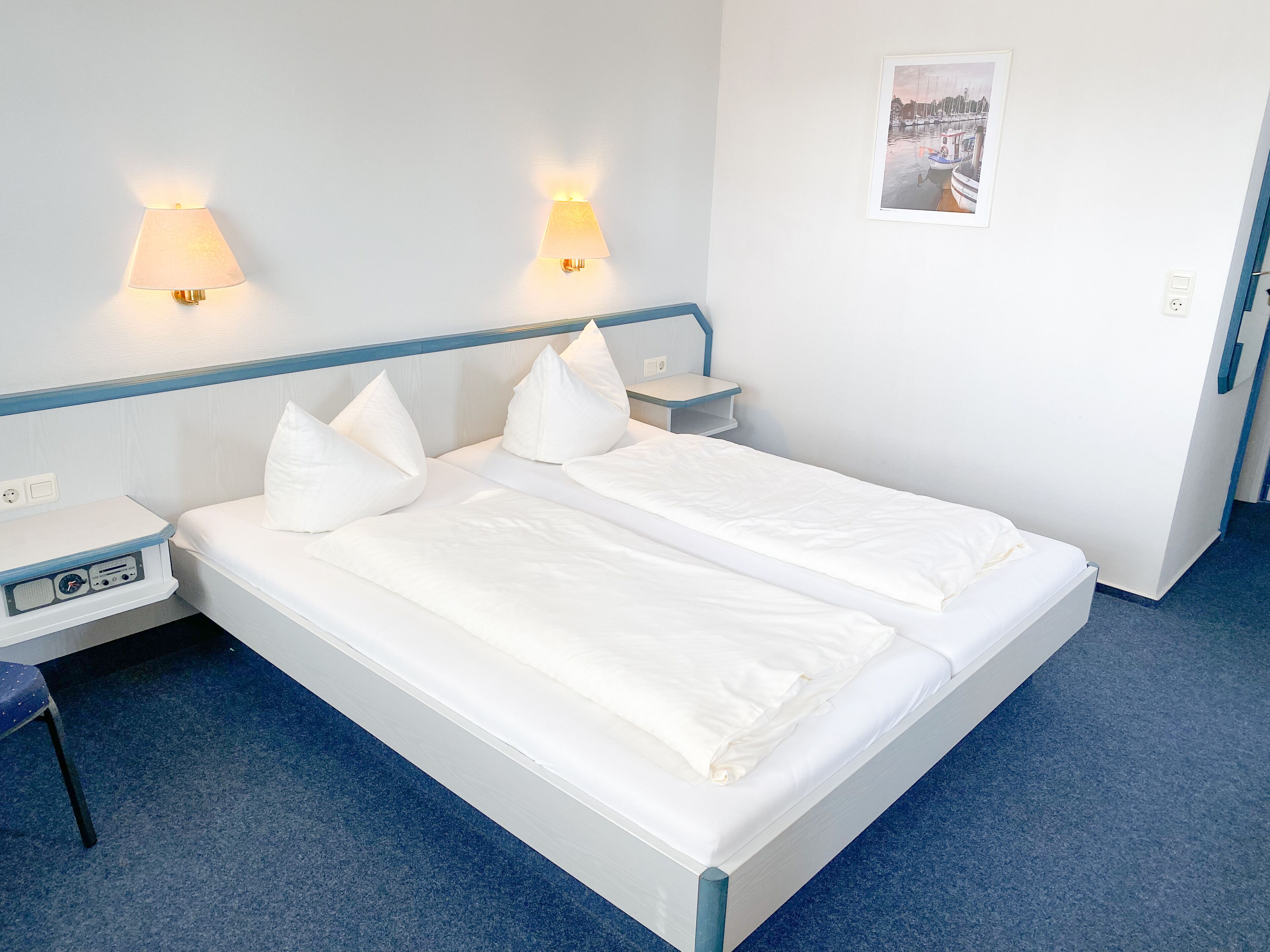 A double bed with white bedding and two bedside lamps.