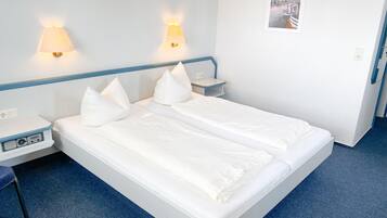 A double bed with white bedding and two bedside lamps.