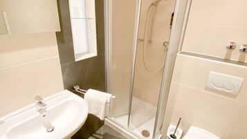 Un bagno moderno con doccia vetrata, lavabo e water.