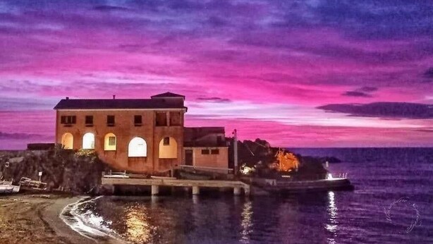 A coastal building with a waterfront view, featuring a prominent structure with multiple windows and a balcony. - Zulin Farm. Air-conditioned accommodations for 4–7 people 011017-AGR-0025 (Levanto)