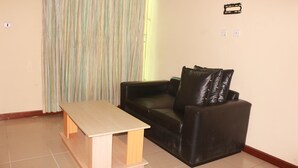 Una sala de estar con una mesa de madera, un sofá de cuero negro y una cortina a rayas.