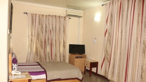 Un dormitorio con cama, televisión, escritorio y silla.