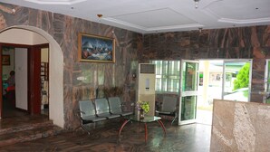 Un vestíbulo con suelo de mármol, un mostrador de recepción y un área de estar con sillones.