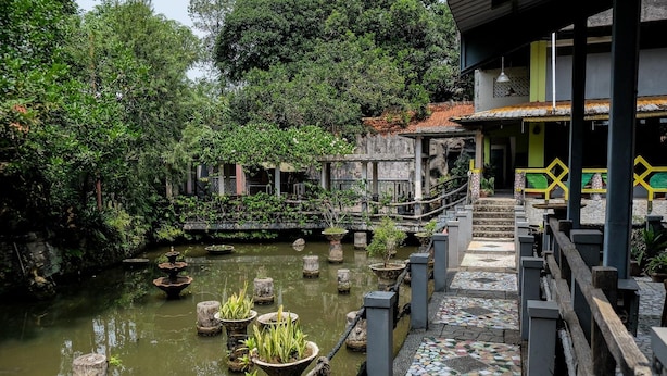 A tranquil garden with a small pond, stone steps, and potted plants. - RedDoorz Plus near Jalan Baru Bogor (Bogor)