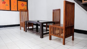 A room with a wooden table and chairs, a staircase, and a wall with floral artwork. - RedDoorz Plus near Jalan Baru Bogor (Bogor)