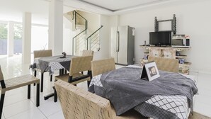 A modern kitchen with a refrigerator, microwave, and a TV mounted on the wall.