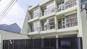 A multi-story residential building with balconies, a gated entrance, and a satellite dish.