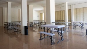 A spacious indoor area with multiple tables and benches, likely a cafeteria or dining hall. - RedDoorz near Akademi Kepolisian Semarang (Semarang)