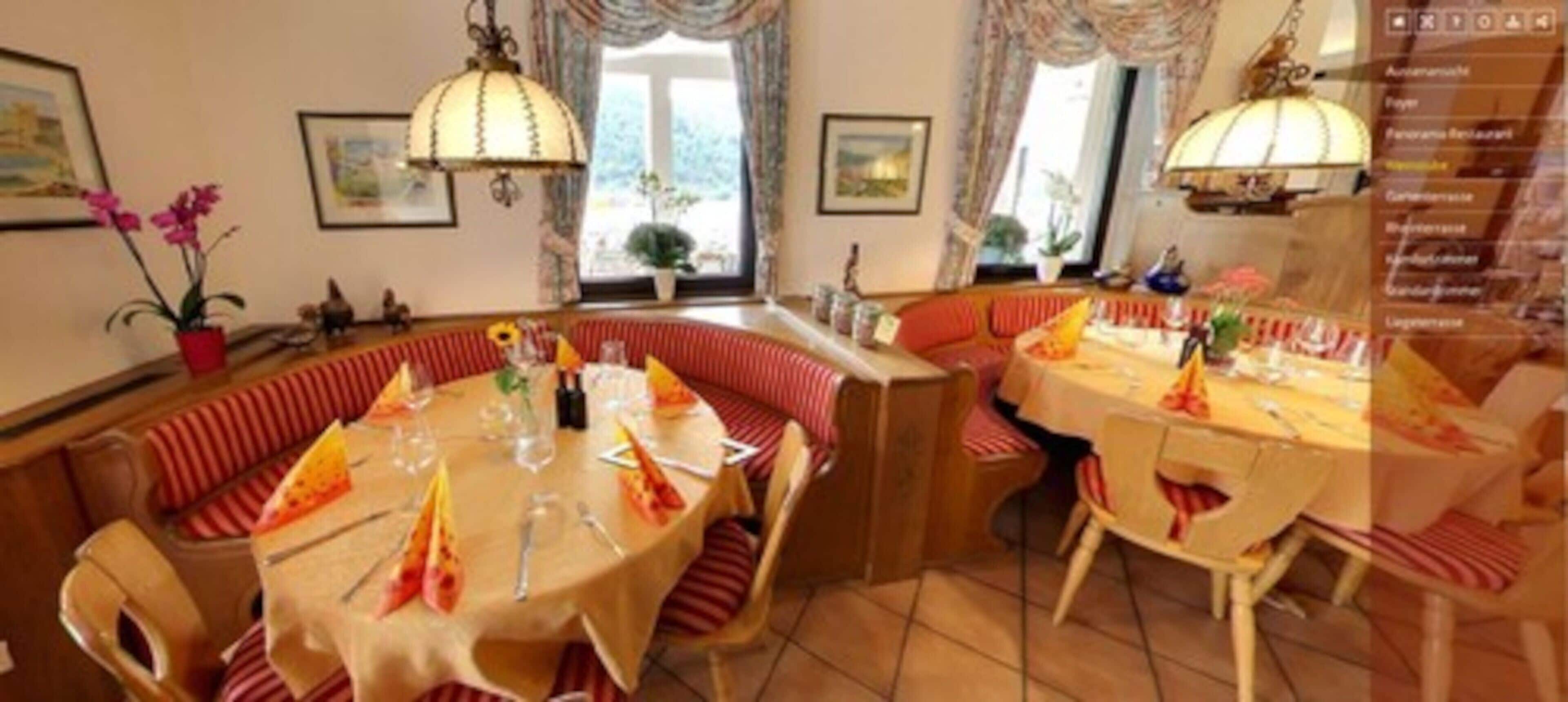 Un comedor con una mesa redonda, asientos tipo cabina a rayas rojas y un candelabro.