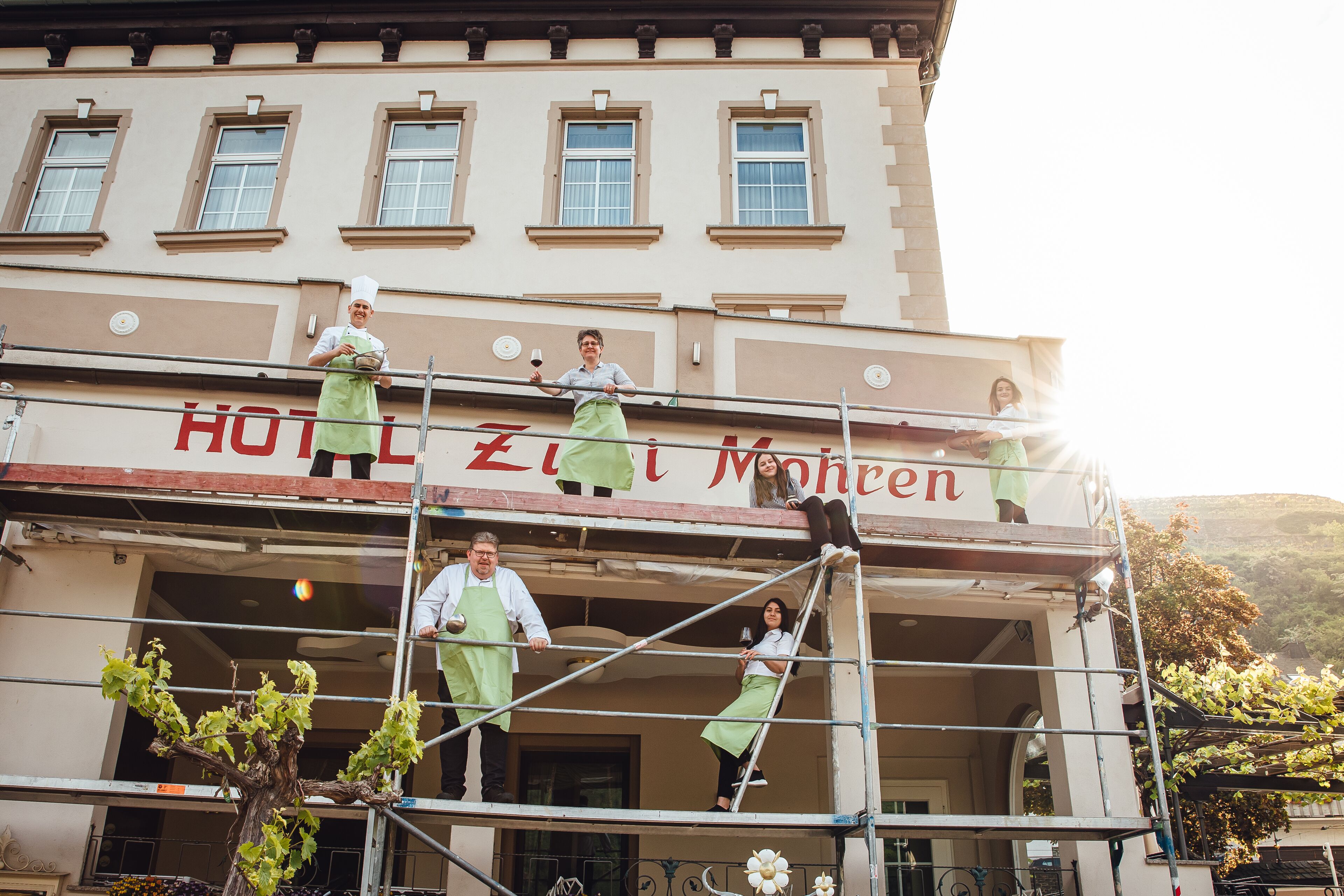 A hotel with a sign reading "HOTEL ZU Mohlen" and three people on scaffolding.