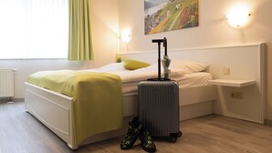 Et hotelværelse med en seng, en kuffert og et par støvler.