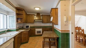 Compact kitchen with a microwave, sink, and wooden table.
