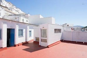 Enjoy breathtaking views from this rooftop terrace with a red-tiled floor and stunning cityscape.