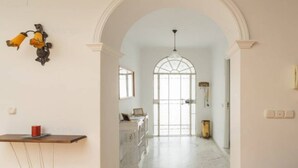 Un corridoio con un arco che dà su una stanza con un'ampia finestra e un lampadario.