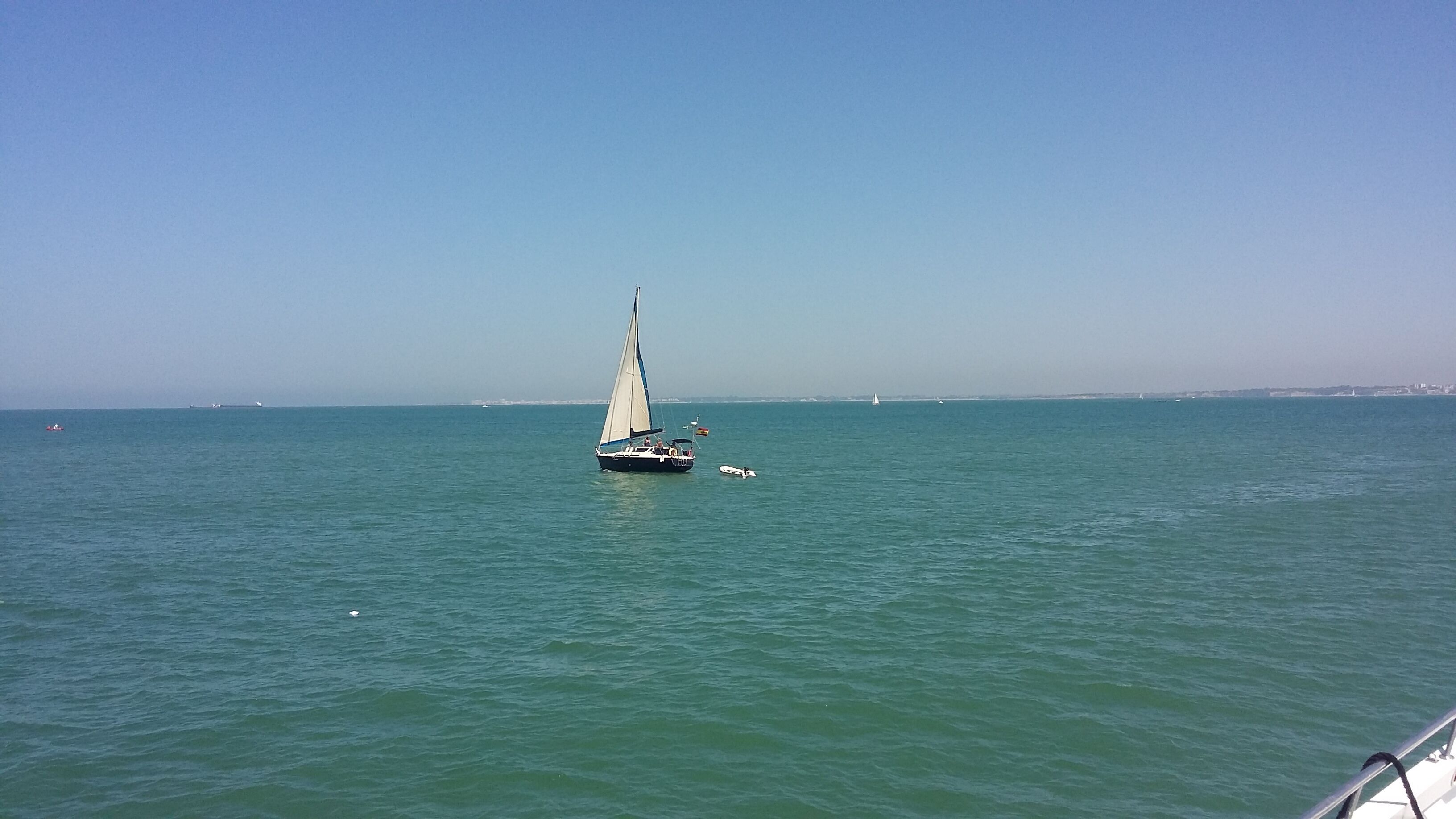 A sailboat on calm waters with a clear sky.