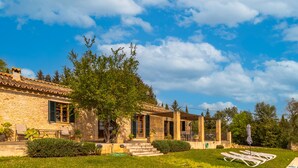 A stone building with a patio, outdoor seating, and a pool.